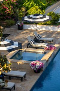 A backyard pool surrounded by tall green hedges and a wooden privacy fence.
